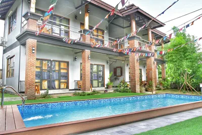 Two-storey hotel with brick pillars and prayer flags above a tiled pool
