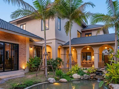 Brick and white villas around palms and a landscaped pond