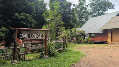 Timber Cave Lodge guesthouse and restaurant sign beside a dirt yard