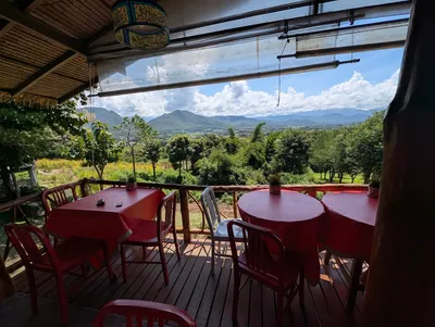 Red tables on a covered deck looking across the Pai valley to the hills
