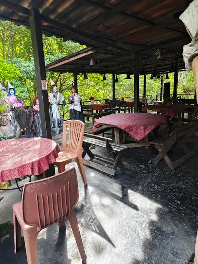 Covered terrace of picnic tables in checked cloths with costumed witch figures at the rail