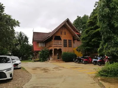 Carved teak house with scooters parked along the forecourt