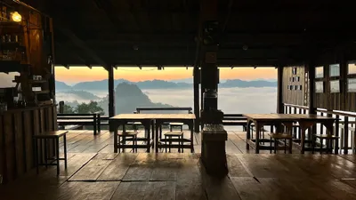 Timber cafe floor and tables open to a sea of cloud over the ridges at dawn