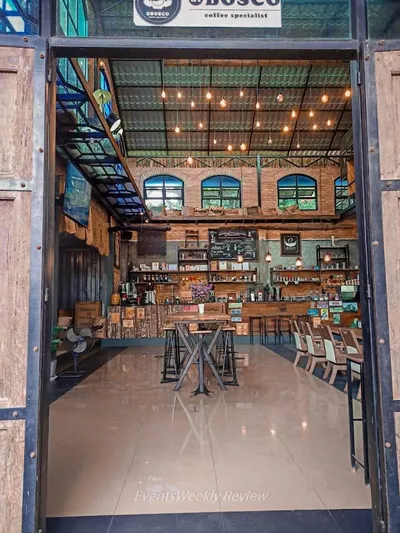 Doorway into a tall brick and timber coffee bar hung with filament bulbs