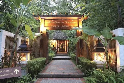 Lantern-lit timber entrance arch reading Fern Resort at the top of a paved path