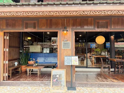 Carved teak shopfront with a coffee bar behind glass and a chalkboard menu on the walkway