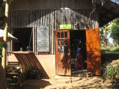 Bamboo and adobe cafe front with a chalked price list under a Wifi Espresso sign
