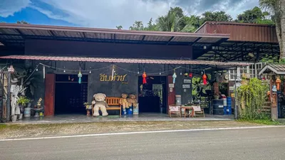Roadside cafe with teddy bears on a bench and lanterns strung along the front