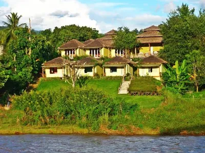 Yellow thatched bungalows on a green bank above the river