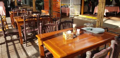 Polished teak tables set with plates and glasses on a sunlit terrace