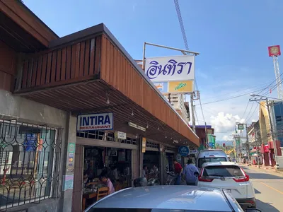 Corner shophouse with an Intira Restaurant sign and diners at street-side tables