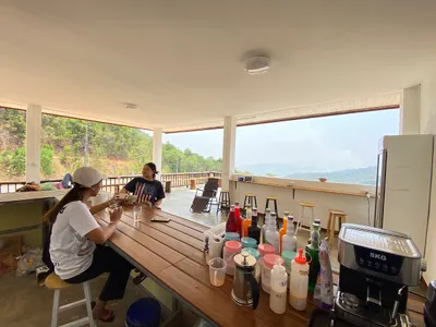 Two women eating at a long counter of syrup bottles on an open hillside terrace