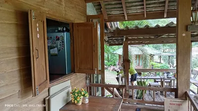 Teak room with shutters open onto a bamboo-roofed deck and garden salas