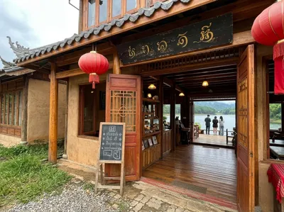 Timber Yunnanese tea house at Ban Rak Thai with red lanterns and open doors onto the lake