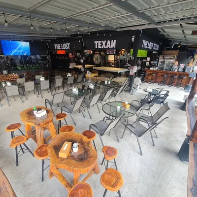 Open-sided bar with a pool table, screens and The Lost Texan on the back wall