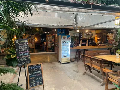 Courtyard tables and chalkboard menus for home-made pizzas beside a lit bar