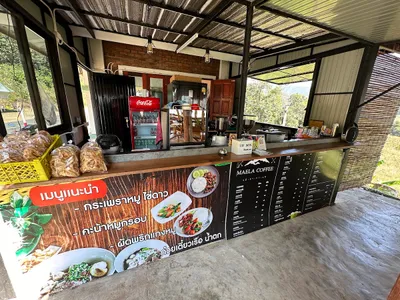Roadside counter with a photo menu, coffee price board and bags of dried noodles