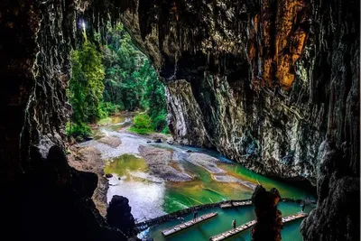Bamboo rafts on the river below the high limestone cave mouth