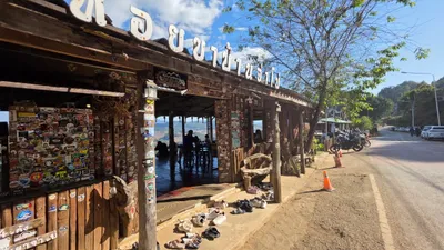 Sticker-covered timber noodle shop above the valley with shoes at the step and bikes on the road
