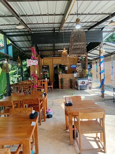 Open-sided restaurant with teak tables and woven fish-trap lampshades
