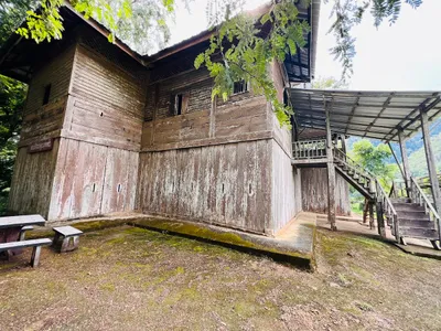 Weathered two-storey timber police station with an outside stair and mossy yard
