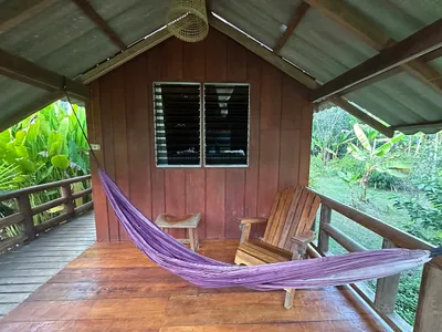 Purple hammock and a timber chair on the veranda of a wooden cabin