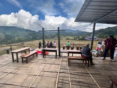 Bamboo deck of benches where people sit looking out over terraced fields