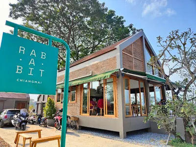 Brick and glass cafe behind a turquoise Rab A Bit sign with bikes parked outside