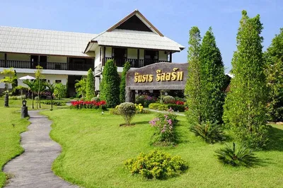 Two-storey timber resort behind a carved stone sign and clipped flower beds