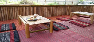 Low bamboo tables and triangle cushions on red mats, one table set with breakfast