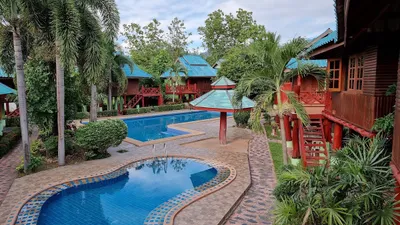 Red timber bungalows around two pools and palms