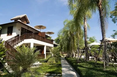 White villa with a timber balcony and parasols along a garden path