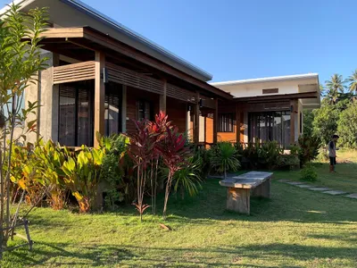 Timber and concrete guest rooms behind a planted lawn and stone bench