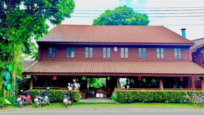 Long two-storey teak hotel with a tiled roof and bikes parked at the roadside