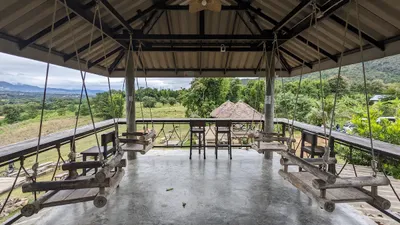Log swing seats hanging from a covered deck looking across fields to the hills