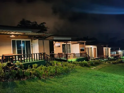 Row of lit cabins with decked verandas on a lawn at night